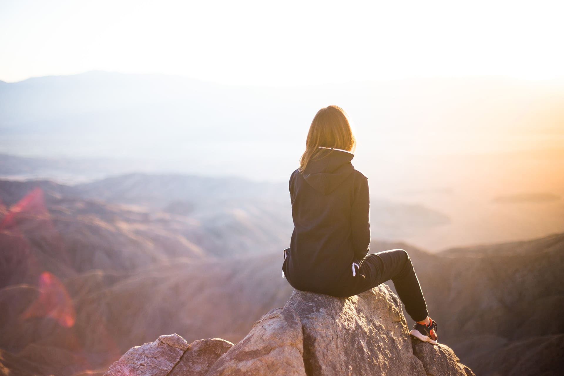 Frau in den Bergen mit Blick auf die Sonne